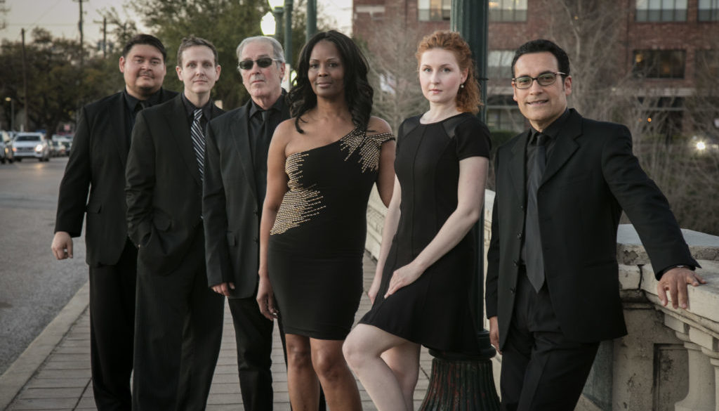 A group of people in black outfits standing on the sidewalk.