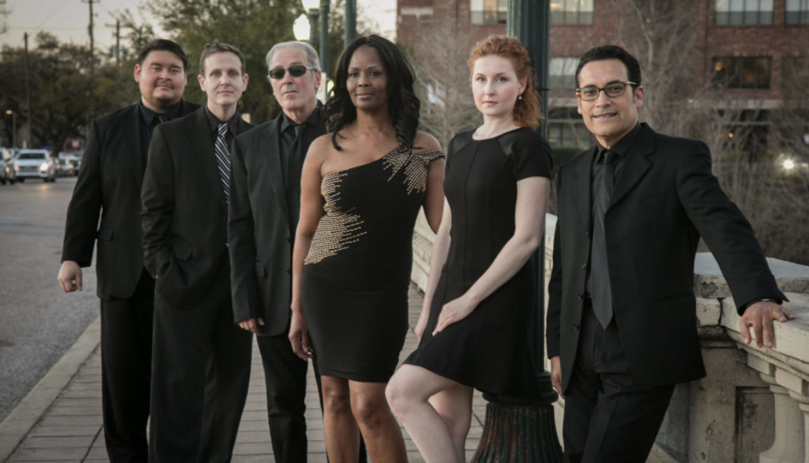 A group of people in black outfits standing on the sidewalk.