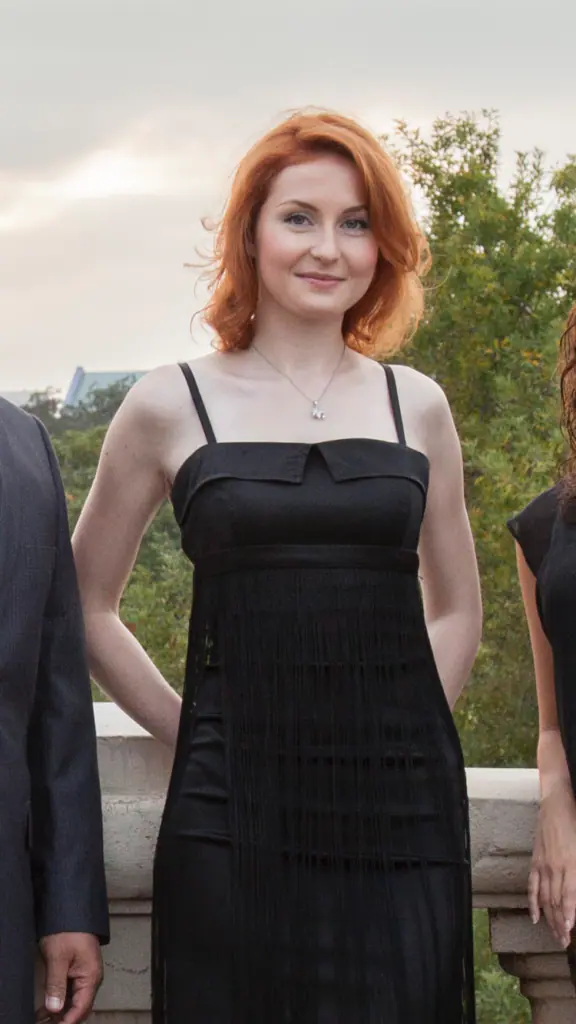 A woman in black dress standing next to another person.